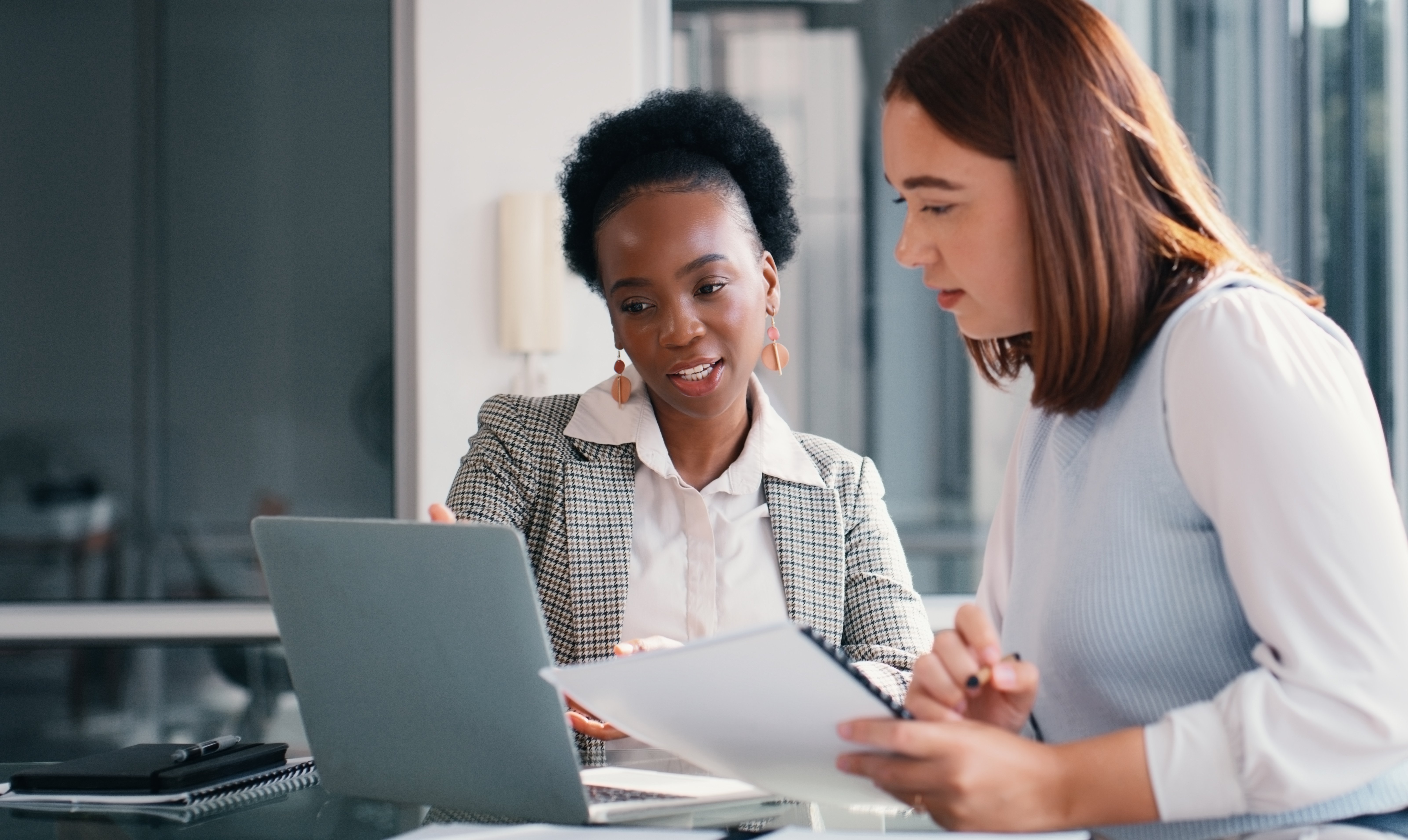 Image depicts two payroll employees strategizing for the now tax on tips act. 